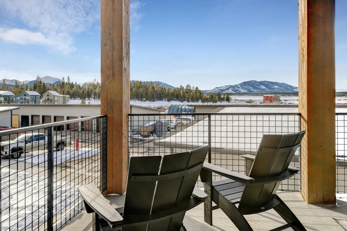 A wooden balcony outfitted with classic Adirondack chairs overlooks a stunning mountain view. The serene setting is perfect for relaxing, enjoying scenic sunrises, or stargazing under clear skies. The presence of the balcony visually connects the guest to the natural beauty and exclusive privacy of the property.