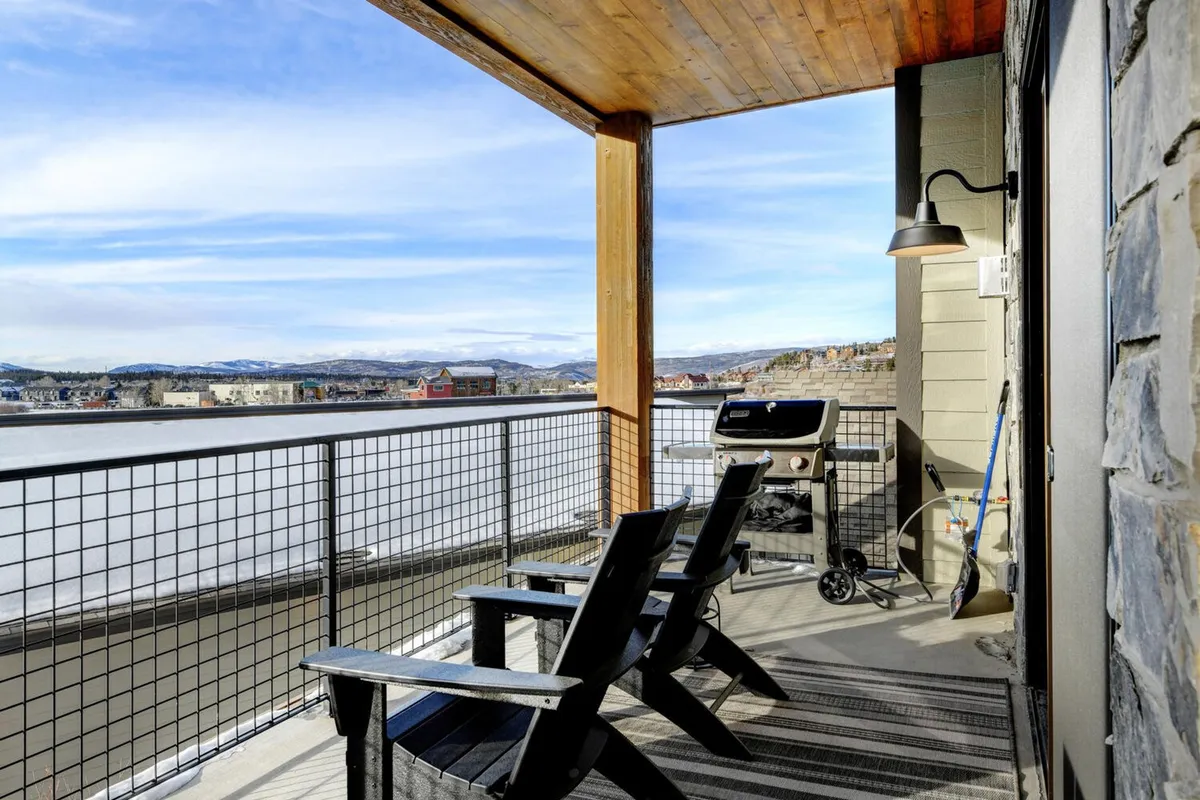 A cozy outdoor BBQ area featuring a grill, comfortable Adirondack chairs, and an open view of the mountains. The space is designed for socializing, hosting sunset feasts, or simply soaking in the scenery.