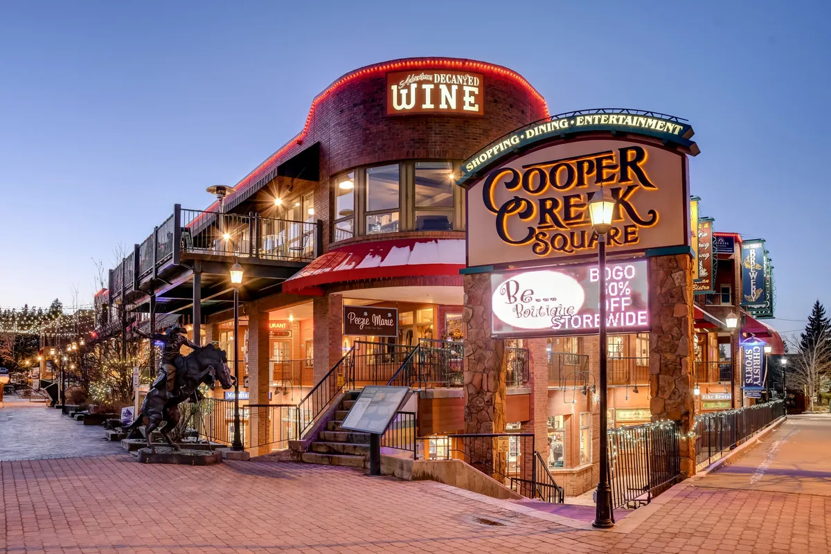 Cooper Creek Square's sign and decorative lights mark the entrance to a lively shopping and dining plaza. The area is adorned with sculptures and festive lighting, hinting at nearby entertainment and curated experiences just a short walk from the property.