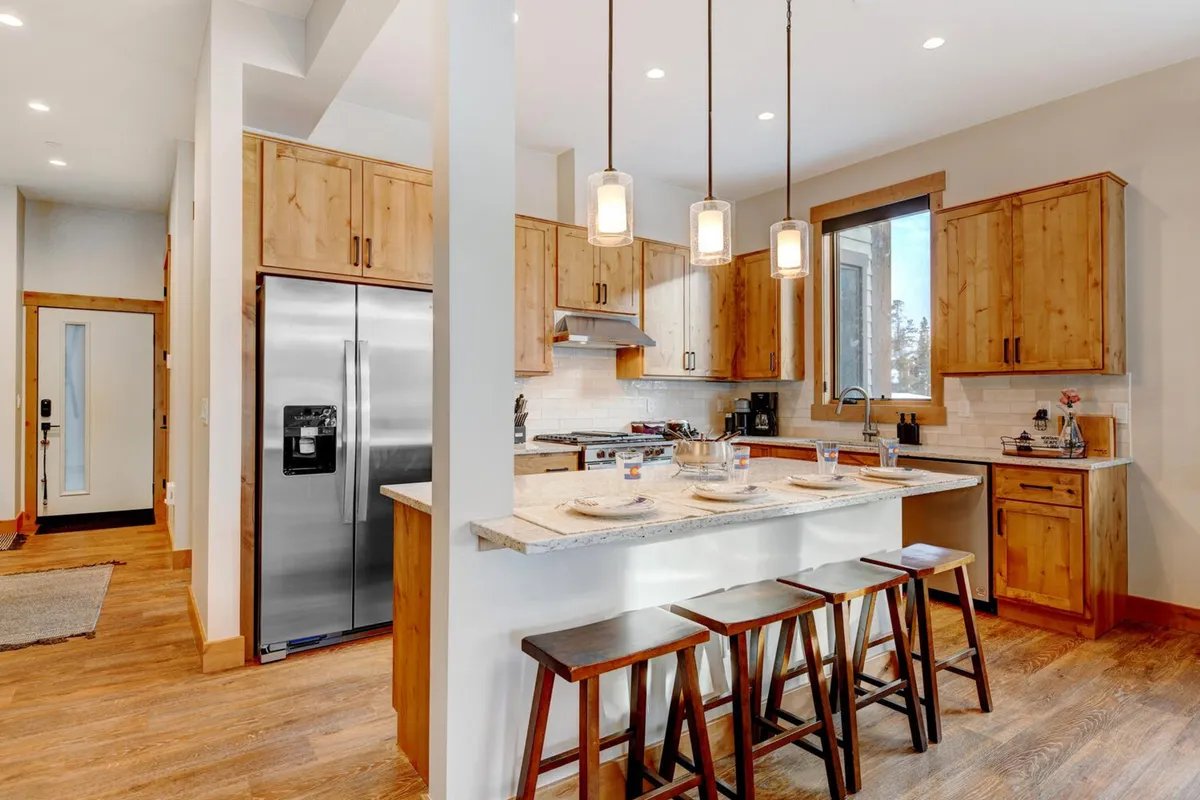 A welcoming kitchen featuring a spacious island countertop with bar stools, warm wooden cabinets, and elegant pendant lighting. The setup invites casual gatherings, while the island provides ample space for meal preparation and socializing. The arrangement and fixtures highlight the gourmet nature of the kitchen and its suitability for entertaining.