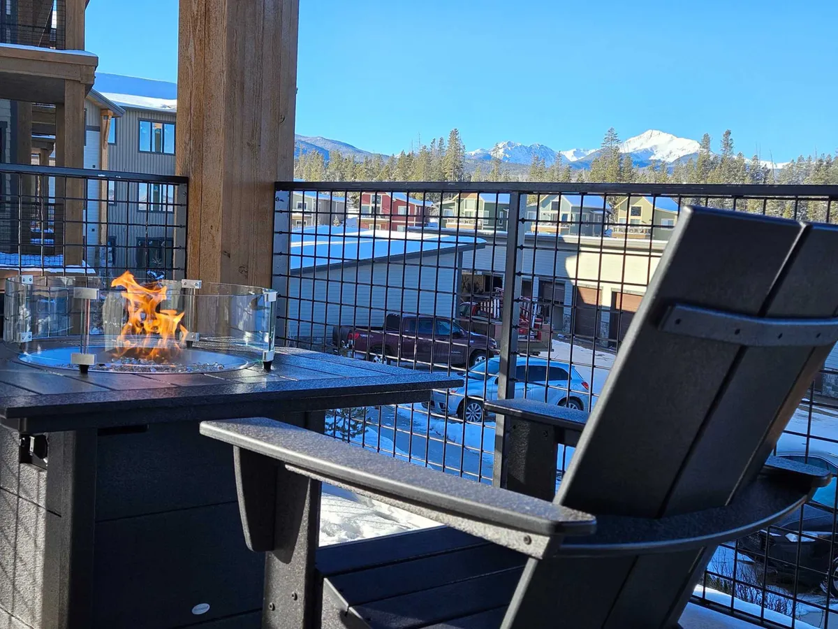 An inviting exterior space featuring a cozy fire pit, Adirondack chair, and panoramic views of mountains. The setting is ideal for socializing, relaxing after a day of activities, or enjoying the changing seasons with friends and family.